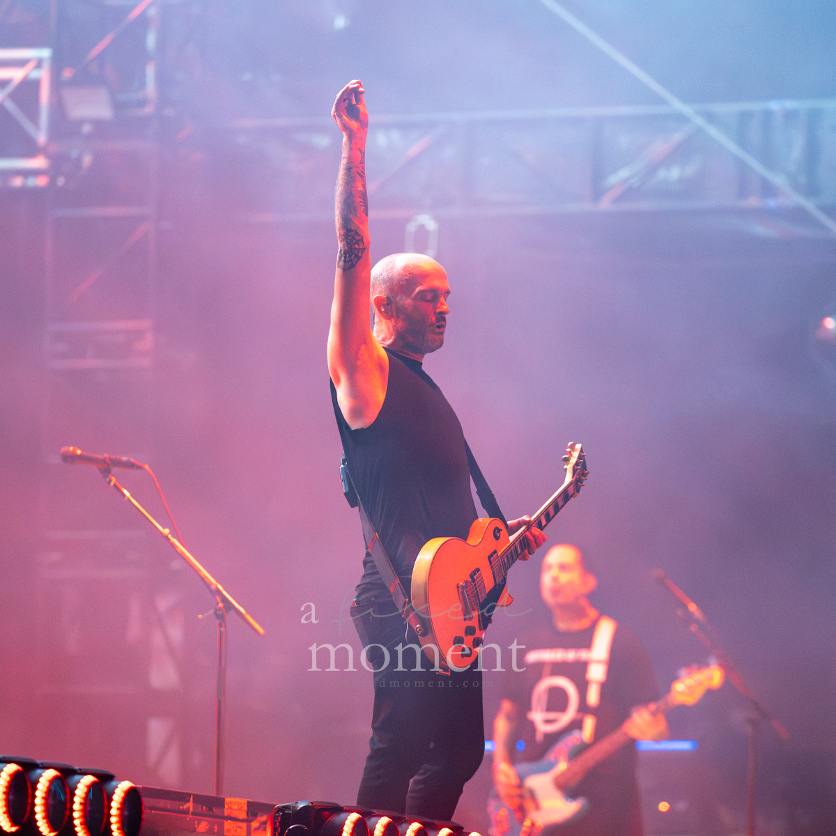 Rise Against guitarist raises an arm while performing at Riot Fest