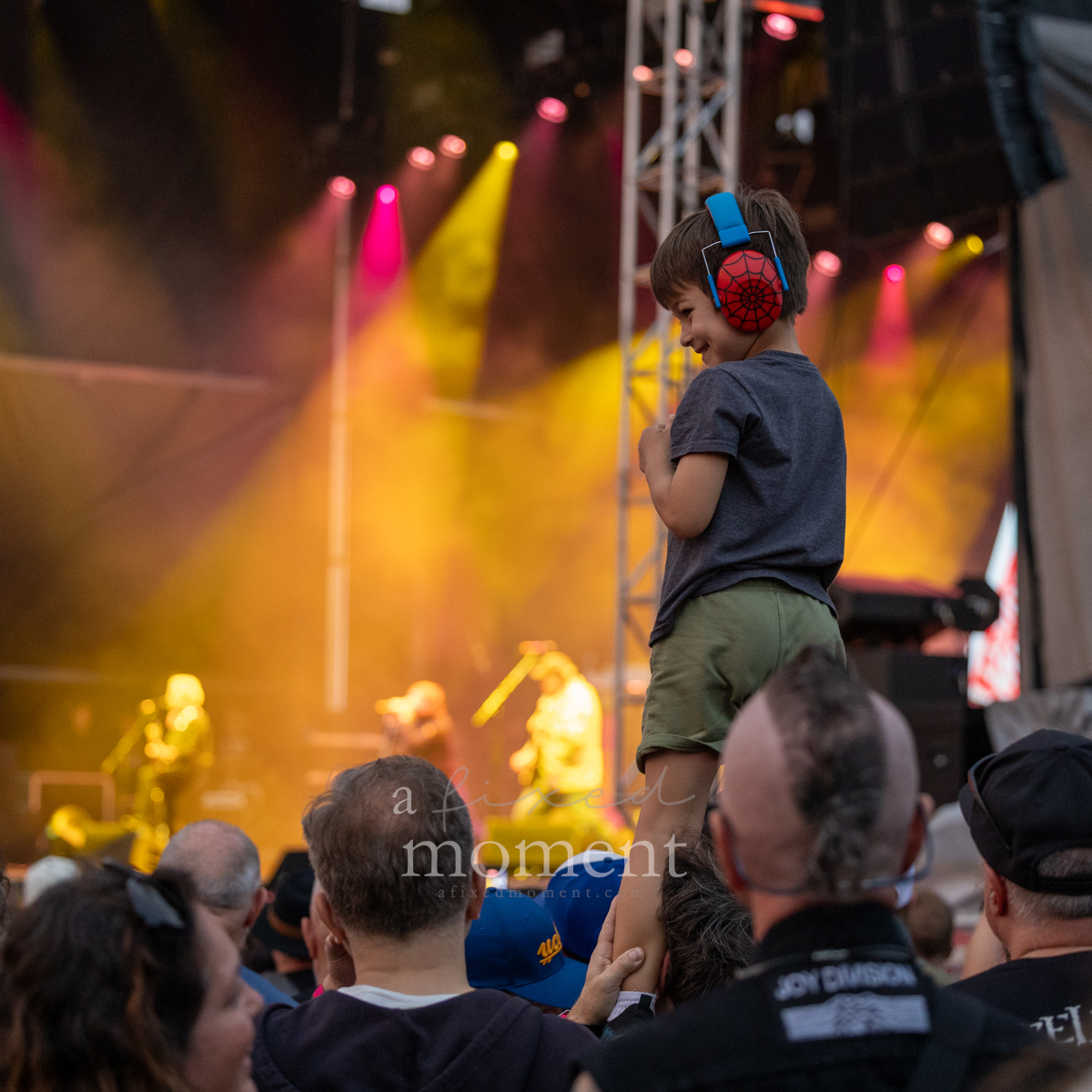 Young fan wearing Spider-Man hearing protection watches Sex Pistols at Riot Fest