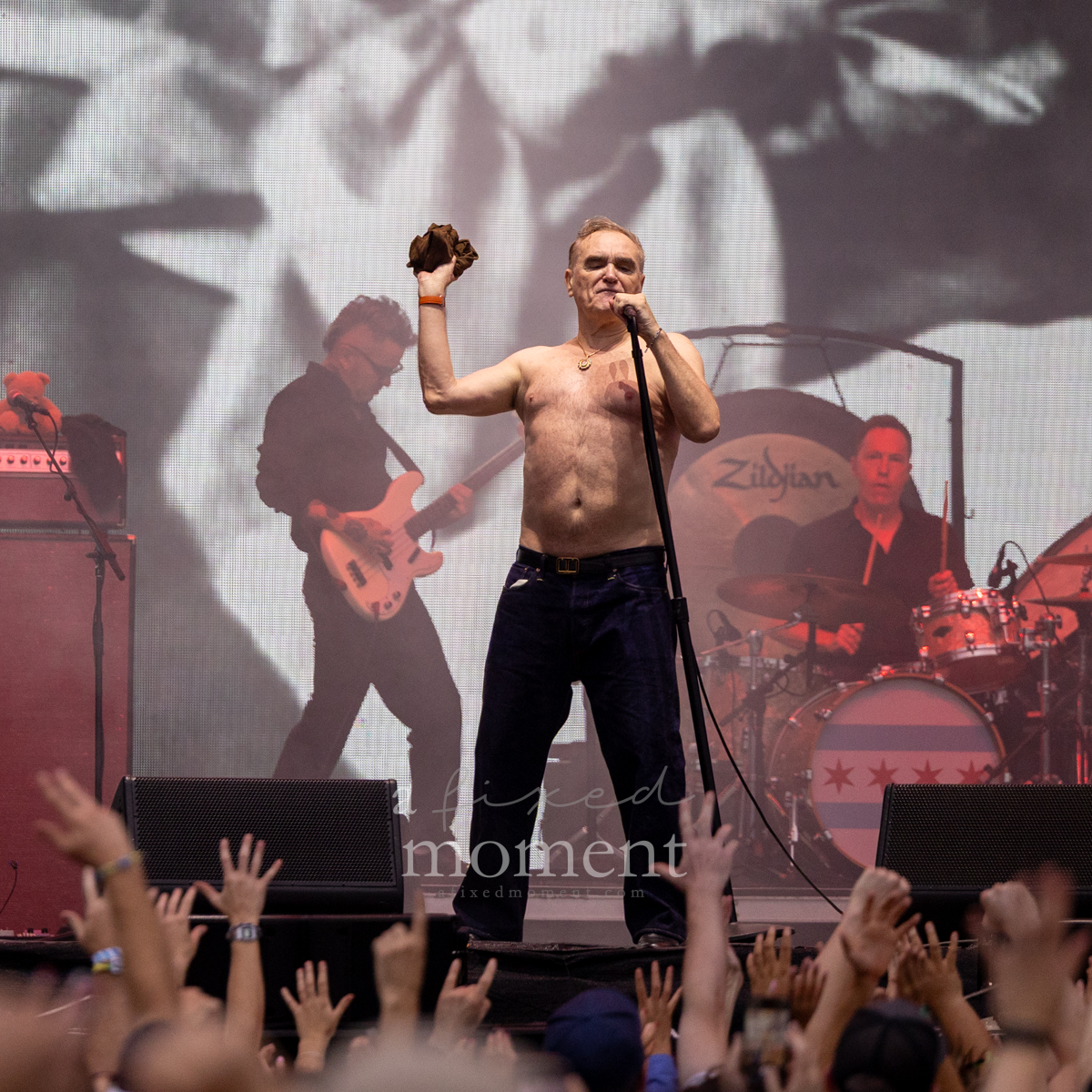 Morrissey performs shirtless as audience members reach toward the stage at Riot Fest