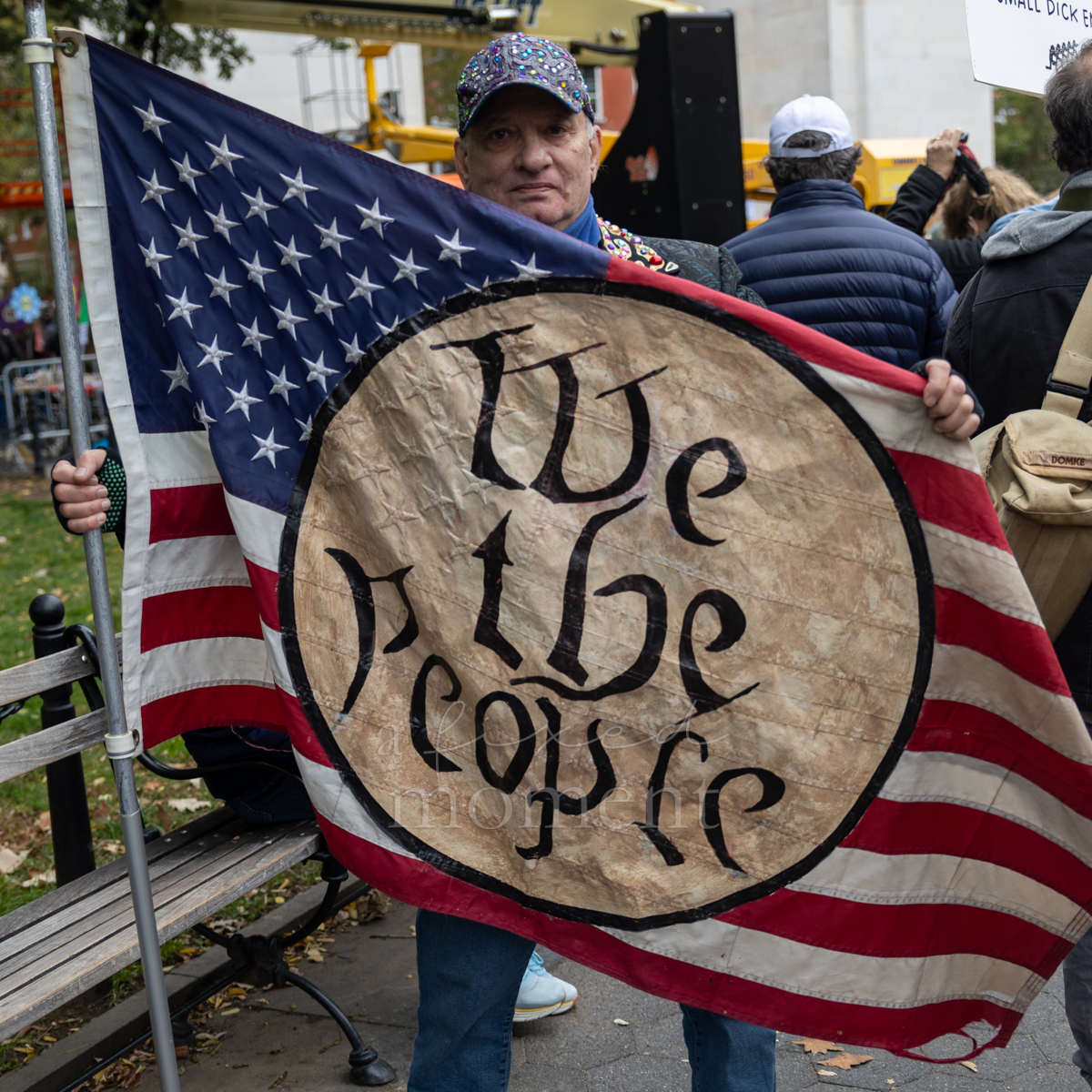 An attendee holds a flag bearing the words We the People.