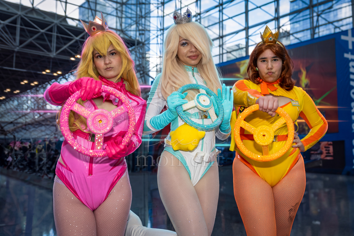 Three cosplayers with colorful costumes and heart-shaped props at New York Comic Con 2026