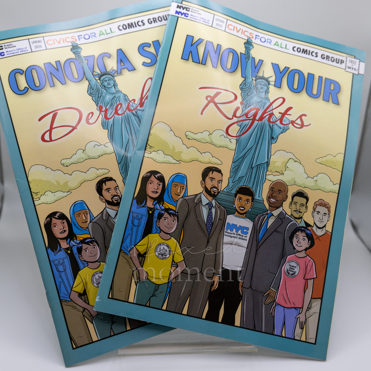 English and Spanish editions of the Know Your Rights comic overlap, displaying illustrated Statue of Liberty covers.