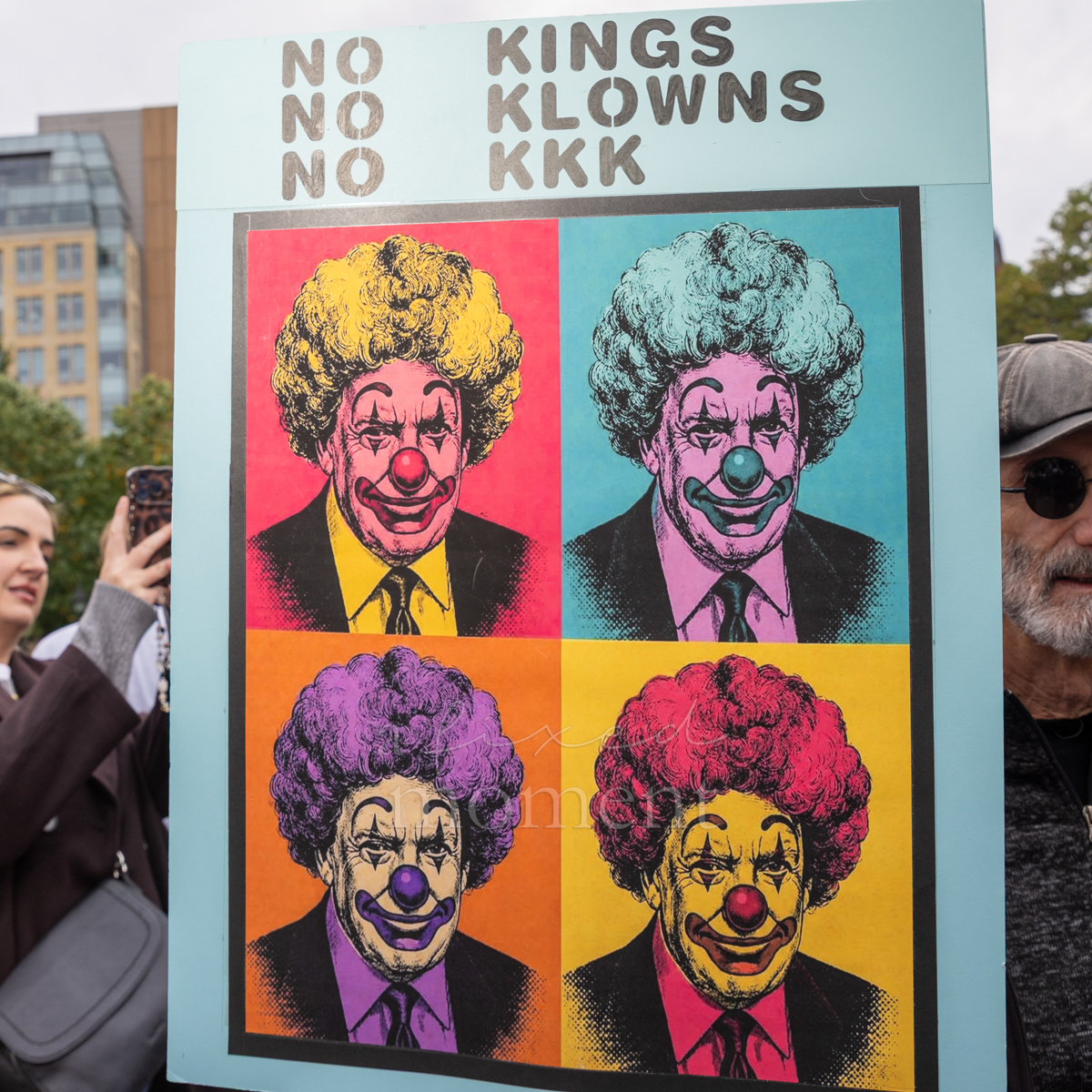 A pop-art sign combines caricatures with No Kings, No Klowns and No KKK slogans.