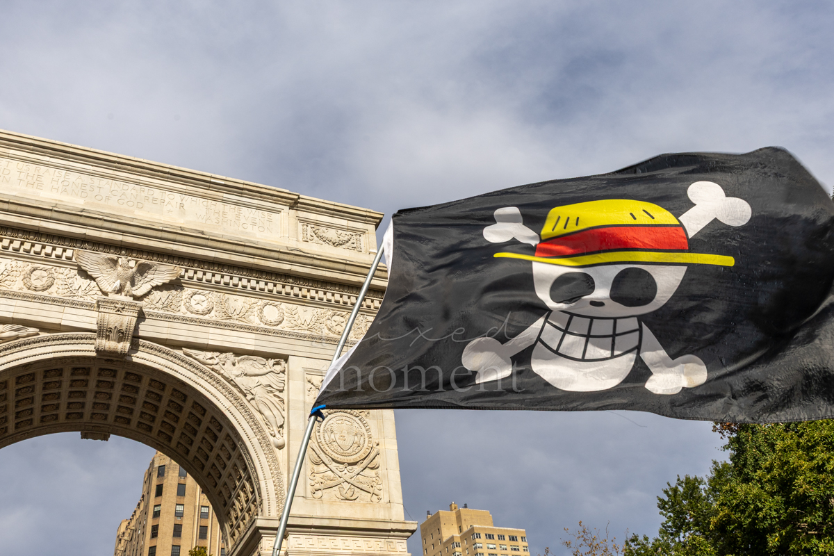 A Straw Hat Pirates flag from One Piece flies beside the Washington Square Arch.