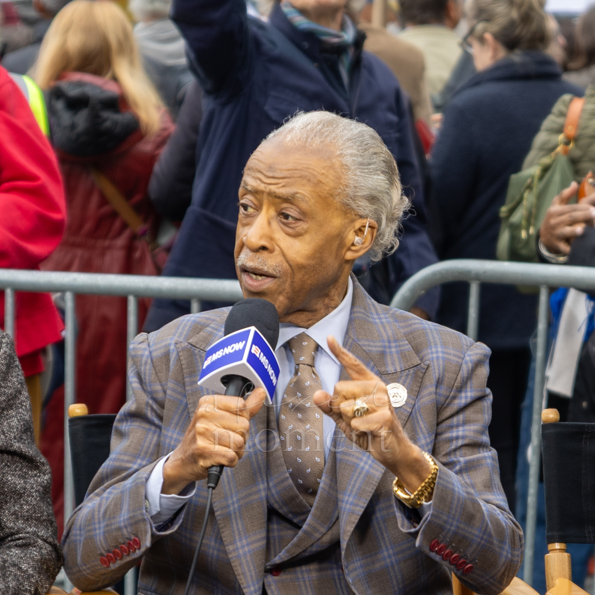 A seated participant speaks into a news microphone during the gathering.