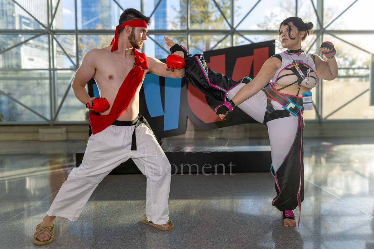 Ryu and Juri cosplayers stage a fighting pose beside the NYCC sign.