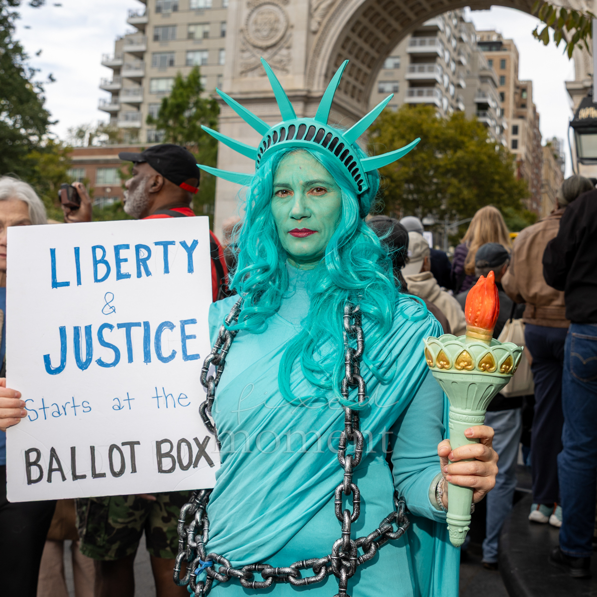 An attendee dressed as the Statue of Liberty holds a sign connecting liberty and justice with voting.