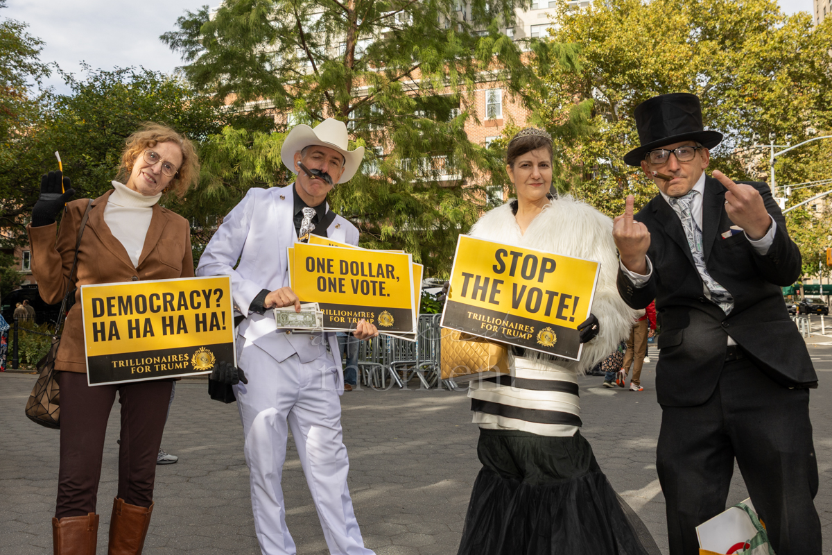 Attendees use satirical Trillionaires for Trump signs to criticize wealth and political power.