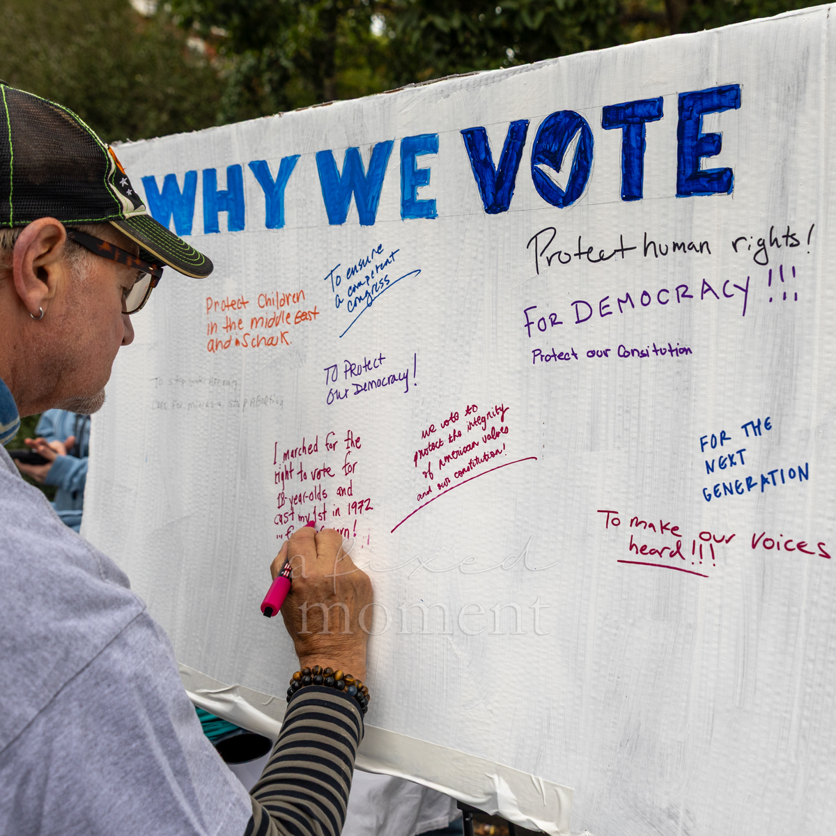 An attendee adds a handwritten response to the Why We Vote board.