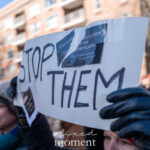 A demonstrator at the 50 50 1 march in New York City on February 17, 2025, holds up a handmade sign reading "STOP THEM," with sections of the U.S. Constitution taped to it. The sign is slightly bent from the wind, and the bold, black lettering stands out against the white background. The taped clippings contain text from the Constitution, including a quote attributed to George Washington about the responsibility of citizens in upholding democracy.
The protester, wearing black leather gloves and a knit beanie, grips the sign firmly while participating in the march. The background shows a blurred crowd of other demonstrators, dressed for the cold weather, with some wearing scarves and winter hats. The setting is in an urban environment, with residential buildings and street signs visible.
This image captures the spirit of civic resistance and political activism, with protesters invoking the Constitution to emphasize their message. The inclusion of historical text reinforces the argument for protecting democratic values and resisting perceived threats to governance.