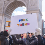 A smiling protester in a shiny black puffer jacket, white knit beanie, sunglasses, and white gloves holds up a large white sign with colorful bold letters reading "F* TRUMP."** The background features the iconic Washington Square Arch in New York City, marking the location of the 50 50 1 march on February 17, 2025. The demonstrator's confident stance and bright smile contrast with the serious political message of the sign.
Surrounded by a crowd of fellow protesters dressed in warm clothing, the scene reflects the passionate civic engagement and resistance present at the event. The use of bright, rainbow-colored text on the sign adds a creative and visually striking element to the political statement.
The 50 50 1 march brought together activists advocating for democracy, accountability, and social justice, with participants using bold signage to express their views. This image captures the spirit of public dissent and free speech in the heart of NYC.