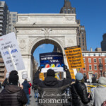 A large crowd gathers at Washington Square Park in New York City on February 17, 2025, for the 50 50 1 march, holding bold protest signs in front of the iconic Washington Square Arch. Demonstrators raise messages opposing authoritarianism, with several bright yellow signs reading:
"In the Name of Humanity, We REFUSE to Accept a Fascist America!" (from RefuseFascism.org)
A prominent handmade sign in the foreground states:
"When the power of PEOPLE is STRONGER than the PEOPLE in power!"
In the background, a large blue banner reads "LGBTQ+ Students and School Staff, WE'RE HERE FOR YOU", showing solidarity with marginalized communities.
The clear blue sky and towering buildings of Greenwich Village frame the protest scene as people clad in winter coats stand in unity, raising their voices for democracy. The demonstrators, many wearing hats and gloves, show a diverse range of ages and backgrounds, emphasizing the collective stand against fascism and political oppression.
This protest scene highlights the urgent call for resistance, civic engagement, and the fight for human rights, symbolized by the unity and determination of those gathered in one of New York City’s most historic public spaces.