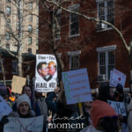 A diverse group of demonstrators gathers at the 50 50 1 march in New York City on February 17, 2025, holding up an array of protest signs denouncing oligarchy, authoritarianism, and corporate influence in politics.
One of the most striking signs in the center features a digitally altered image of Elon Musk and Donald Trump kissing, with the text "Elon + Felon HAIL NO!" and a caption crediting the image as satire. Nearby, another sign reads "DOGE: Dangerous Oligarchs Grabbing Everything", playing on the popular cryptocurrency Dogecoin acronym to criticize wealth concentration.
Other visible signs include:
"STOP THE COUP"—a strong opposition to political corruption and authoritarianism.
"HANDS OFF CANADA"—suggesting concerns about foreign interference or influence.
"CURE FASCISM"—calling for action against rising authoritarian tendencies.
"No Dictators in the USA"—a direct rejection of authoritarian leadership.
The crowd is bundled in winter clothing, with many wearing knit hats, scarves, and gloves, suggesting the protest is taking place in cold weather. The red brick buildings and tree-lined street provide a distinctly urban backdrop, reinforcing the city environment of the demonstration.
The atmosphere is charged with activism and political engagement, as participants passionately hold up their handmade signs, advocating for democracy, equality, and resistance against oppressive forces.