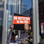 At the Picket Tesla protest organized by Rise and Resist (@risenresistnyc) on March 1, 2025, outside the Tesla Showroom in Manhattan (860 Washington Street, NYC), a demonstrator prominently holds up a striking black, red, and white sign that reads: "NO DICTATORS in the USA" featuring an image of Donald Trump. The protester, wearing a light blue button-down shirt, glasses, and a black wide-brimmed hat, raises the sign high with both hands while looking ahead.
The background includes a reflection of clouds on the glass windows of the Tesla showroom, adding a dramatic effect. Other protesters are visible holding various signs with messages opposing corporate power and political figures. A smaller white sign to the left features the text "$TOP" with a crossed-out image, while another partially visible sign in the crowd states "OVERTHROW" in bold yellow letters. The location, situated in the heart of Manhattan, is marked by a nearby "No Standing" street sign and brick buildings lining the streets.
This protest, led by Rise and Resist (@risenresistnyc), is part of a broader movement against corporate influence and authoritarianism. Demonstrators gathered outside the Tesla showroom to criticize both Elon Musk and broader political issues related to billionaires and power.