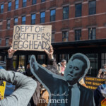 At the Picket Tesla protest organized by Rise and Resist (@risenresistnyc) on March 1, 2025, outside the Tesla Showroom at 860 Washington Street, NYC, demonstrators hold bold signs denouncing Elon Musk, political corruption, and corporate greed.
In the center, a protester raises a cardboard sign that reads:
"DEPT OF GRIFTERS & EGGHEADS"
The sign critiques government and corporate elites, aligning with the protest's broader message against billionaire influence.
In the foreground, a large cutout of Elon Musk in a suit with a raised arm is prominently displayed, serving as a visual focal point of the protest. Nearby, another protester holds a black sign with yellow text reading:
"OVERTHROW THE SHADOW PRESIDENT"
To the left, a protester waves a small American flag, while another holds a black sign that reads:
"FK MUSK"** in bold white letters.
The crowd consists of diverse individuals, many wearing sunglasses, hats, and scarves, indicating cool weather. Some are capturing the event on their phones, while others hold signs condemning Trump’s impact on the Constitution and corporate power structures. The red-brick buildings in the background contrast with the protest's vibrant energy, as the demonstrators take over the sidewalk in front of Tesla’s showroom.
This protest, led by Rise and Resist (@risenresistnyc), reflects the group’s stance against economic inequality, tech industry corruption, and political overreach.