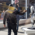 At the Picket Tesla protest organized by Rise and Resist (@risenresistnyc) on March 1, 2025, outside the Tesla Showroom at 860 Washington Street, NYC, a tense moment unfolds as a security guard in black clothing and beige boots gestures toward a protester inside the showroom. The protester, wearing a blue jacket and a face mask, holds a small American flag in one hand and a black sign with white lettering that reads, "THIS BILLIONAIRE IS DESTROYING OUR COUNTRY" in the other.
This striking image is captured from the outside looking in, with reflections of protesters and their signs merging with the showroom's sleek interior. The Tesla humanoid robot display is visible in the background, symbolizing the company's futuristic branding, while the presence of protesters inside contrasts sharply with the polished corporate setting.
Outside, reflections of demonstrators holding yellow protest signs with messages against Elon Musk, corporate greed, and economic injustice can be seen on the showroom's glass windows, blurring the lines between activism and commerce. The New York City streetscape, complete with a yellow taxi and brick buildings, is also visible in the reflection, grounding the protest in its urban setting.
The Rise and Resist (@risenresistnyc) demonstration highlights growing concerns about billionaire power, political influence, and the role of corporations like Tesla in shaping the economy and government policy. The presence of security inside the showroom underscores the tension between activists and corporate interests.