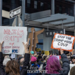 On March 1, 2025, outside the Tesla Showroom at 860 Washington Street, NYC, demonstrators at the Picket Tesla protest, organized by Rise and Resist (@risenresistnyc), raise bold signs condemning corporate and political power consolidation. Two prominent signs in the foreground read "NAZIS OUT OF THE WHITE HOUSE AND NYC!" in red marker and "STOP THE TRUMP-MUSK COUP" on an orange-bordered placard, emphasizing the protest’s message against authoritarianism, wealth-driven influence, and perceived threats to democracy.
The Tesla storefront serves as a backdrop, while a wooden humanoid figure sculpture looms in the background, adding an eerie contrast between the themes of protest and technological dominance. Other signs in the crowd reference economic injustice, corporate corruption, and Musk’s controversial political stances. Participants, clad in winter attire, stand unified in defiance, holding their handmade signs high, representing a collective grassroots opposition to oligarchic power and threats to democratic norms.