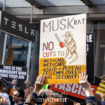 At the Picket Tesla protest outside the Tesla Showroom at 860 Washington Street, NYC, on March 1, 2025, demonstrators hold up signs condemning Elon Musk's influence and corporate greed. A prominently featured handmade sign depicts a rat labeled "MUSKRAT" wielding a chainsaw, alongside the message: "NO CUTS TO MEDICAID, MEDICARE, PEPFAR, USAID, FED. EMPLOYEES, SOC. SECURITY." The artwork and bold lettering highlight concerns about billionaire-led policies affecting public welfare.
Other protest signs in the background read "OVERTHROW THE SHADOW PRESIDENT," "THIS IS THE IMMIGRANT WHO TOOK YOUR JOB," and "NAZI NAZI NAZI"—emphasizing fears of authoritarian control and economic inequality. The demonstrators, part of the Rise and Resist movement (@riseandresistnyc), advocate for protecting government-funded social services, combating corporate overreach, and holding billionaires accountable.
The protest unfolds in front of the Tesla showroom, with the luxury brand's sleek, modern aesthetic contrasting sharply with the grassroots activism and handmade signs. The event draws attention to the role of powerful elites in shaping policies that impact healthcare, workers, and social security.