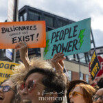 At the Picket Tesla protest outside the Tesla Showroom at 860 Washington Street, NYC, on March 1, 2025, demonstrators rally with passionate energy, raising signs that call for economic justice and corporate accountability. Organized by Rise and Resist (@riseandresistnyc), the protest features activists holding up strikingly colorful signs. One bright orange sign reads "Billionaires Should Not Exist!", while another vibrant blue sign proclaims "People Power" with green lightning bolts emphasizing grassroots activism.
The crowd is diverse and energized, chanting in unison. Many protesters wear sunglasses, and their faces reflect determination and joy. A woman in the foreground, wearing red-rimmed glasses and a white scarf, sings alongside others, their voices echoing through the streets. Additional protest signs in the background include "DOGE is a Criminal Enterprise", "Pull the Plug on Musk", and "Musk WTF?", reinforcing the movement’s broader concerns about corporate influence, cryptocurrency manipulation, and economic inequality.
The moment is filled with defiant optimism, as the protesters channel their collective outrage into action, calling for systemic change and highlighting the power of collective resistance.