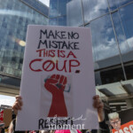 At the Picket Tesla protest outside the Tesla Showroom at 860 Washington Street, NYC, on March 1, 2025, a demonstrator holds a striking protest sign high above their head. The sign reads "MAKE NO MISTAKE, THIS IS A COUP. RESIST!" in bold black and red letters, accompanied by a raised red fist clutching cash—a symbol of financial and political resistance. The sky and surrounding glass buildings reflect the intensity of the moment, as protesters rally against corporate overreach and billionaire influence.
In the foreground, another protest sign featuring Donald Trump’s face with the word “FASCIST” in bold white letters reinforces the movement’s message, linking Elon Musk's actions to larger threats against democracy. The Rise and Resist NYC (@riseandresistnyc) movement organized the demonstration, drawing activists who oppose economic inequality, oligarchy, and the influence of billionaires in politics.
The protest, featuring chants, speeches, and musical performances from @resistancerevivalchorus, emphasized corporate accountability and grassroots activism. The energy of the crowd, with fists raised and voices unified, captured the growing public discontent with Musk’s role in media, technology, and governance.