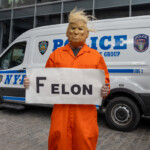 A protester wearing an orange prison jumpsuit and a mask resembling former President Donald Trump stands in front of an NYPD police van during the Picket Tesla protest at 860 Washington Street, NYC, on March 1, 2025. The individual holds a handmade sign reading "FELON" in bold black letters, making a direct political statement. Their posture is firm as they stare toward the camera, emphasizing the message of their costume and sign.
The background features an NYPD Strategic Response Group (SRG) police vehicle, glass-covered buildings, and other demonstrators, highlighting the event's protest atmosphere. This moment captures the theatrical and symbolic nature of political demonstrations, where protesters use costumes, satire, and visual messaging to amplify their stance.
This demonstration, organized by Rise and Resist NYC (@riseandresistnyc), targeted Elon Musk, Tesla, and the broader influence of billionaires in politics and corporate power.