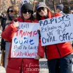 Two women pose together holding powerful protest signs during the Women's March on March 8th, 2025, in Washington Square Park, New York City. They stand side by side, smiling confidently and demonstrating camaraderie.
The woman on the left wears a bright red puffer coat, black sunglasses, and a black knit hat. Her sign reads: "I'd call TRUMP a CUNT But he lacks Depth + Warmth."
The woman on the right sports a dark jacket with red accents, black sunglasses, a dark knit hat, and gloves, displaying her sign which says: "RAPISTS Belong in Jail NOT the OVAL OFFICE."
The message directly targets former president Donald Trump, criticizing his behavior and actions. Around them, a large crowd of demonstrators participates actively, underscoring a unified stance against injustice and advocating for accountability.