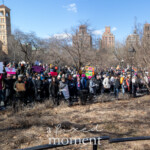 A panoramic view captures a massive, diverse crowd gathered at Washington Square Park during the Women's March on March 8th, 2025, in New York City. The demonstrators, spread across the expansive park grounds, enthusiastically hold up a multitude of colorful protest signs advocating for women's rights, social justice, political accountability, and equality.
Visible among the crowd are signs with strong political messages, including:
"FDT" (a commonly used abbreviation meaning "F*** Donald Trump")
Several bright pink and vibrant signs supporting reproductive rights, feminism, and intersectional activism.
The participants, dressed warmly in jackets, coats, hats, scarves, and winter gear, reflect a wide range of ages, backgrounds, and communities united for a common cause. The demonstration is visibly spirited and energized, highlighting solidarity, commitment, and advocacy for social and political change.