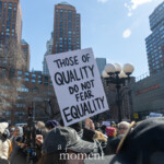 A powerful message stands tall at Union Square during the NYC Women’s March 2025, with a bold sign that reads "THOSE OF QUALITY DO NOT FEAR EQUALITY." The sign is held up by a protester in the middle of a dense crowd of activists, surrounded by individuals of diverse backgrounds. The cityscape of New York City, with tall buildings and the iconic digital clock at 14th Street, serves as the backdrop. A person wearing a pink pussy hat, a well-known feminist symbol, is visible in the crowd, reinforcing the theme of gender equality and activism. The energy of the demonstration is evident as people stand together in solidarity, advocating for human rights, social justice, and gender equality.